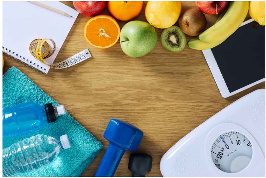 Healthy lifestyle setup with fresh fruits, dumbbells, measuring tape, water bottle and scale for chronic pain management through nutrition and exercise