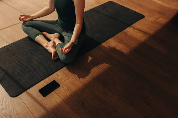 Woman sitting cross-legged on a yoga mat practicing meditation for back pain relief
